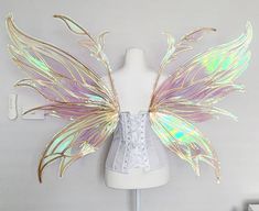 a white mannequin with gold and purple wings on it's back side