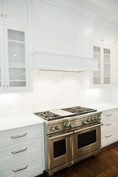 a kitchen with white cabinets and stainless steel stove top oven in the center of the room