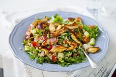 a blue plate topped with salad next to a fork