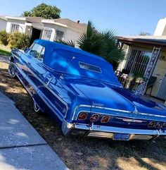 an old blue car parked in front of a house