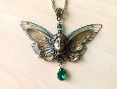 Art Nouveau angel necklace, butterfly fairy in old gold brass and green crystal, transparent wings, face necklace: this superb original necklace consists of two pairs of fairy wings, transparent butterfly wings, slightly glittery and tinged with green. In the center, is fixed an old gold brass plaque, art nouveau style, representing a goddess or fairy face with butterfly wings. Under the fairy is hung a drop of emerald green Swarovski crystal, set old gold. The necklace is connected, by an emera