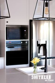 two lights hanging over a kitchen sink next to an oven