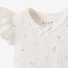 a white sweater with a bow on the collar and sleeves, that says eleganti