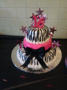 a zebra print cake decorated with pink and black ribbon, stars and number on top