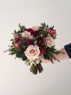 a person holding a bouquet of flowers in their hand with the other hand reaching for it