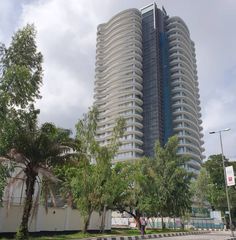 a tall building sitting on the side of a road next to trees and palm trees