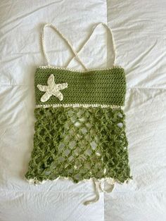 a green crocheted bag with a starfish on it sitting on a bed