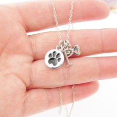 "Keep your pet close to your heart with this adorable necklace made with three silver plated charms. A cute round charm with a doggy paw imprint, a bone, and your pet's personalized initial. The charms are suspended from a silver plated chain that comes in several lengths to choose from when adding to cart. The paw charm measuring 1/2\" (12mm). If you have any questions, please do not hesitate to contact me. ►►NEED MORE INITIALS ADDED TO THIS NECKLACE? CLICK THE LINK BELOW◄◄ https://www.etsy.com Silver Paw Print Jewelry For Personalized Gift, Personalized Silver Jewelry With Paw Print, Silver Jewelry With Paw Print For Personalized Gift, First Dog, Remembrance Necklaces, Pet Remembrance, Silver Dog, Dog Charm, Personalized Initials