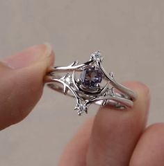 a person is holding a ring with a blue stone in it's center and two white diamonds on each side