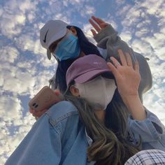 a woman wearing a face mask standing in front of the sky with her hands up