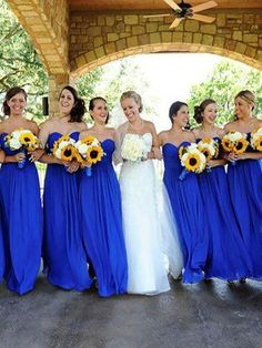 a group of women standing next to each other wearing blue dresses and sunflower bouquets