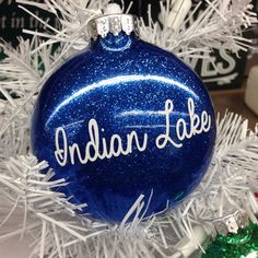 a blue ornament with the word indiana on it sitting on top of a white christmas tree