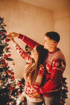 a man and woman standing next to a christmas tree