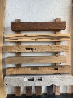 several wooden planks stacked on top of each other in front of a white brick wall