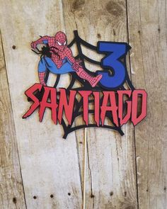 a spiderman cake topper sitting on top of a wooden table