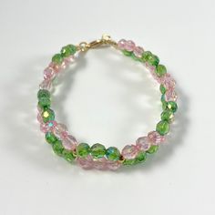 Dressy pink and green twisted faceted glass bead bracelet, round gold accents and gold lobster clasp Green And Pink Bracelet, Pink Czech Glass Bracelets With Faceted Beads, Pink Faceted Beaded Bracelets, Twist Bracelet, Bracelet Inspo, Glass Bead Bracelet, Twisted Bracelet, Memorial Bracelet, Glass Beaded Bracelets