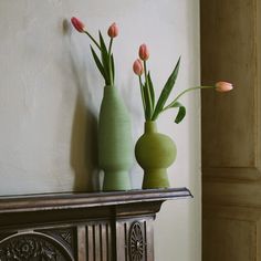 two vases with tulips are sitting on a mantle next to each other