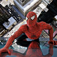 a spider man sitting on top of a building in front of a cityscape