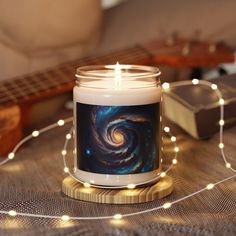 a candle sitting on top of a table next to a string of lights and a guitar