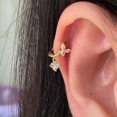 a close up of a person's ear with an earring in the shape of flowers