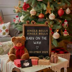 a teddy bear sitting in front of a sign that says jungle bells, jungle bells baby on the way