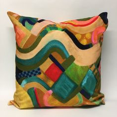 a colorful pillow with an abstract design on the front and back side, sitting on a white surface