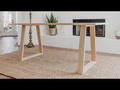 a wooden table sitting on top of a rug in front of a fire place with a potted plant