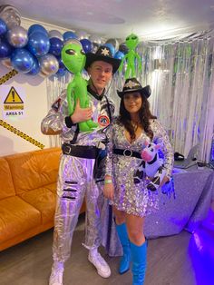 a man and woman dressed up as aliens pose for a photo in front of balloons