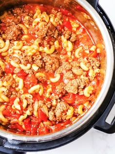 an overhead view of a pot full of pasta and meat in marinara sauce on the stove