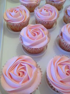 cupcakes with pink frosting sitting on a white tray in the shape of a rose