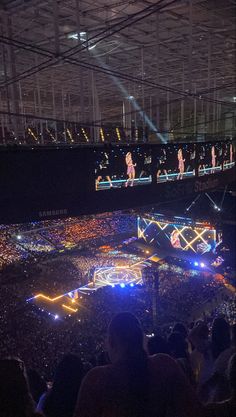 an arena filled with lots of people and lit up stage lights in the middle of it