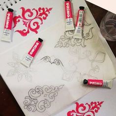 some markers and pens are sitting on top of a drawing paper with red ink in it