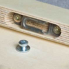 a close up of a metal object on a wooden surface with two screws in the middle