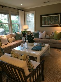 a living room filled with lots of furniture next to two large windows covered in blinds