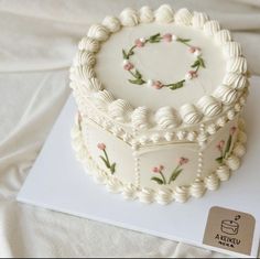 a decorated cake sitting on top of a white tablecloth covered table next to a card