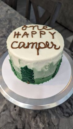 a white cake with green frosting and writing on it that says happy camper