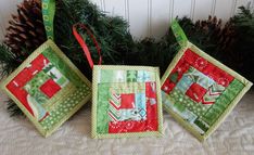 three christmas ornaments sitting on top of a table next to pine cones and evergreen branches