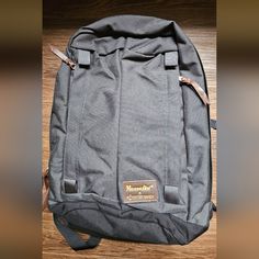 a gray backpack sitting on top of a wooden floor