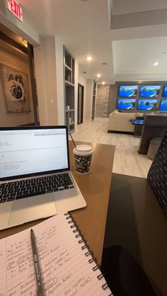 an open laptop computer sitting on top of a wooden desk next to a cup of coffee