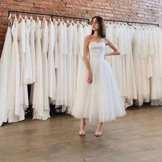 a woman standing in front of a rack of dresses