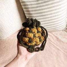 a hand holding a small crocheted object in it's palm on a bed