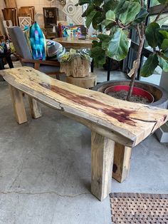 a wooden bench sitting next to a potted plant on top of a cement floor