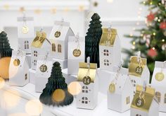 a table topped with lots of white boxes filled with christmas trees and presents on top of it