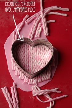 a heart shaped object sitting on top of a table next to knitting needles and yarn