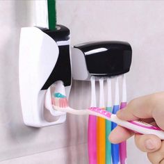 a person holding a toothbrush and toothpaste holder in front of a wall mounted toothbrush holder