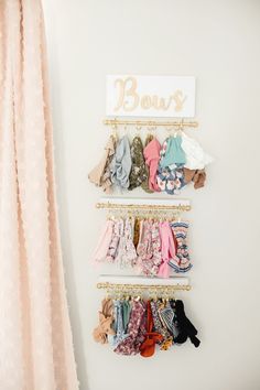 a wall mounted rack with baby's clothing hanging on it and a sign above it