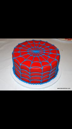 a red and blue spiderman cake sitting on top of a white tablecloth covered table