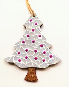 a white ceramic christmas tree ornament hanging on a string with pink and purple squares