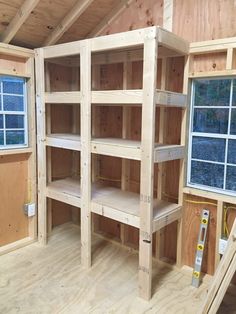 an unfinished room with wooden shelves in the wall and window on the far side that is being built