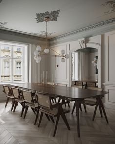 a dining room table and chairs in front of a large window with an ornate chandelier hanging from the ceiling